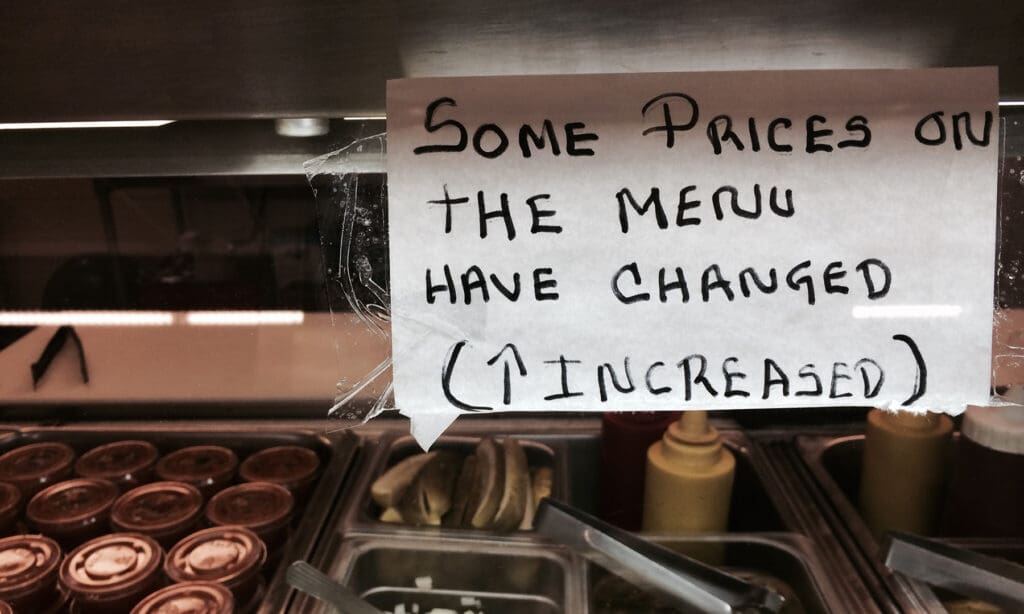 Hung written piece of paper in window of restaurant that says "some prices on the menu have changed. Increase."