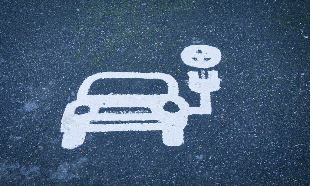 Parking space for electric vehicle painted in white on parking lot.