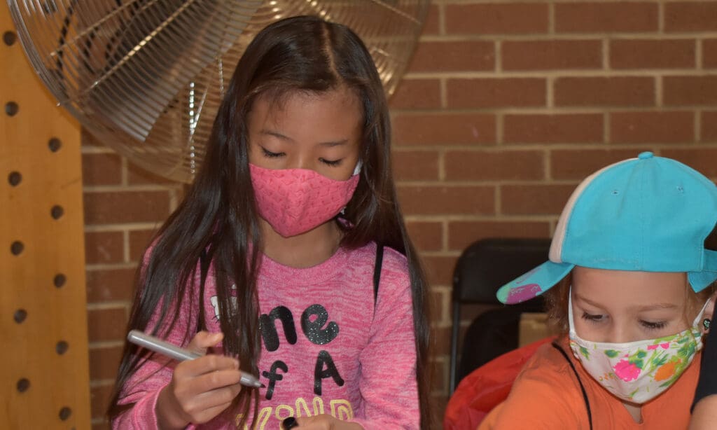 Two kids drawing with masks on