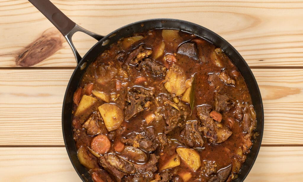 Goat stew in a pan on a wooden table