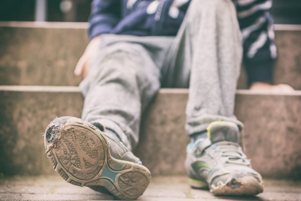 Old broken shoes of a little boy as a symbol for child poverty