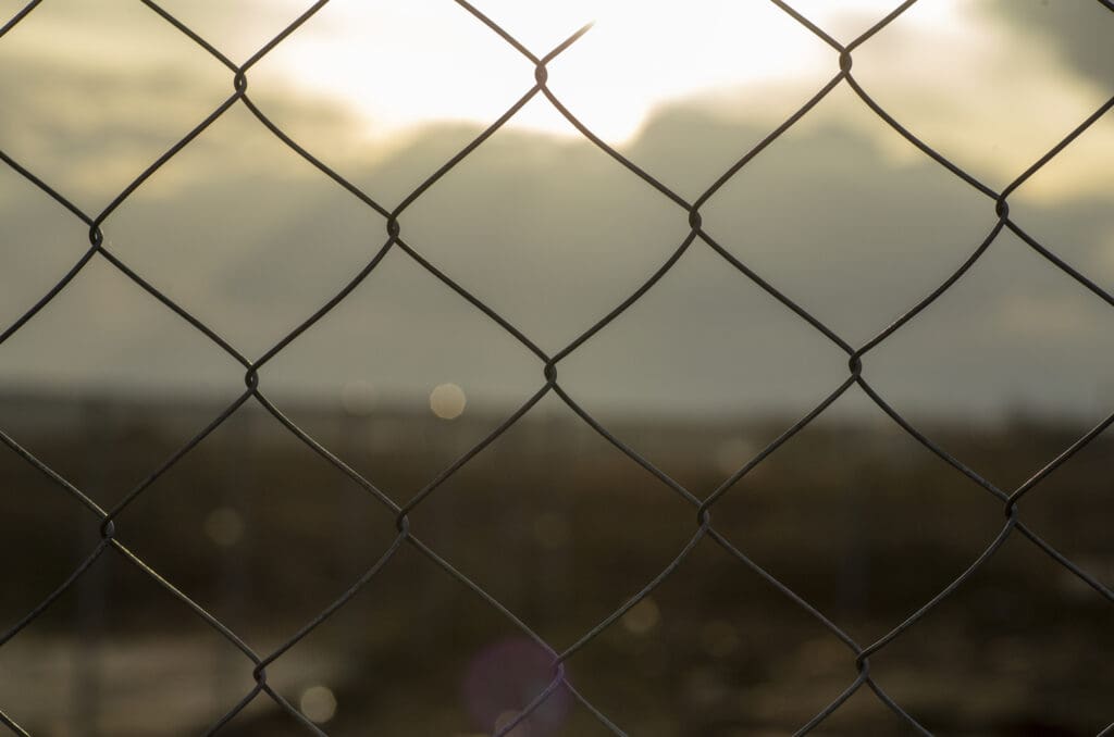 A metal mesh fence enclosing a restricted area (quarantine, prison, production area).