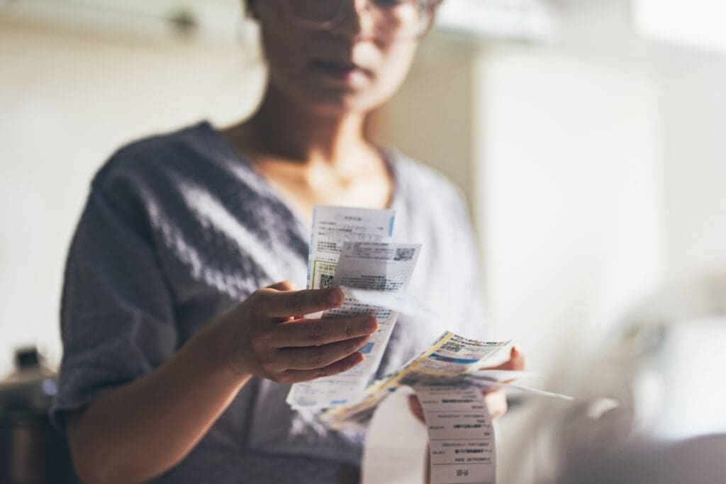 Woman holding paper various expense bills and plans for personal finances at her home.