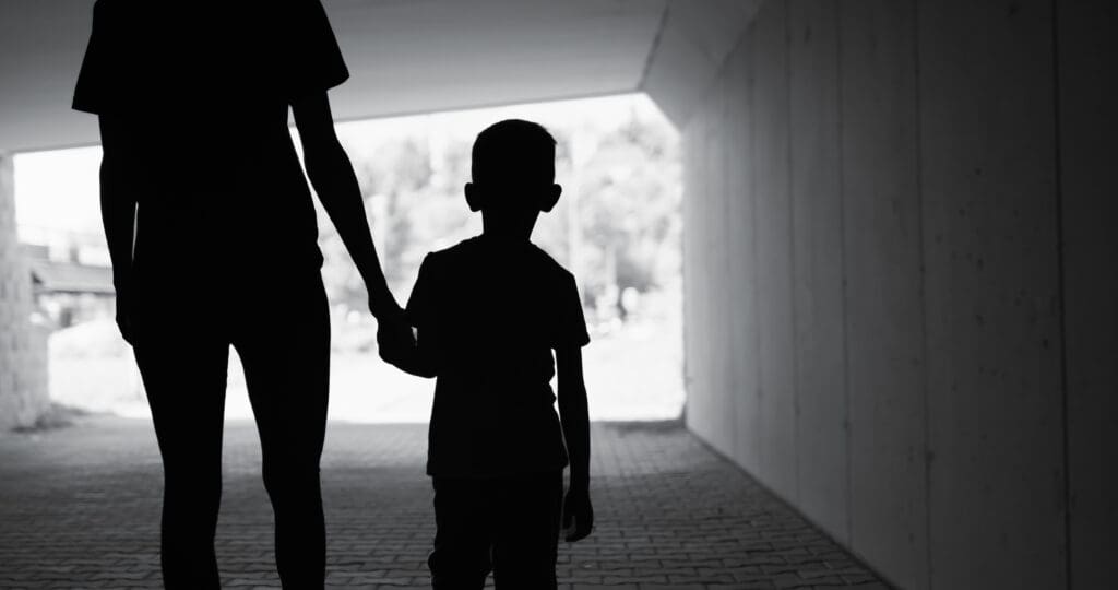 Kid and parent holding hands, dark silhouettes