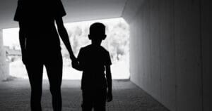 Kid and parent holding hands, dark silhouettes