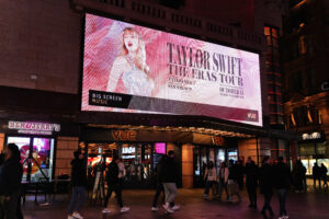 Taylor swift on a screen outside of a stadium, featuring Eras tour