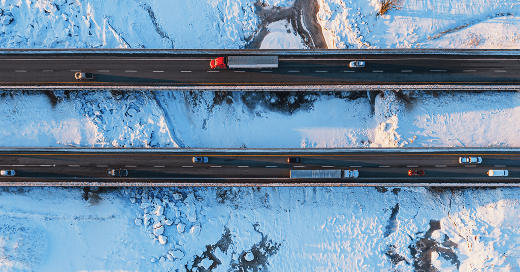 An aerial view of a highway with trucks transporting goods in the winter