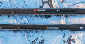 An aerial view of a highway with trucks transporting goods in the winter