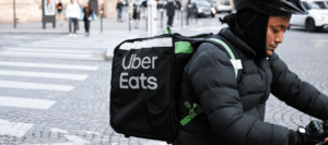 uber eats delivery person of colour on their bike looking down on their phone