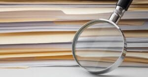 Stack of papers with a magnifying glass resting on them
