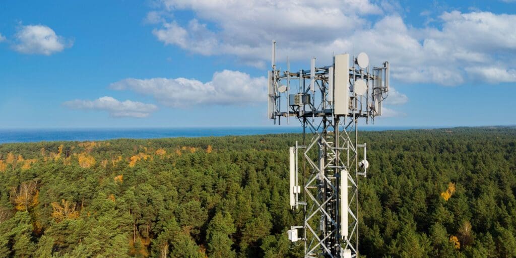 telecommunication tower with antennas for 5g network on forest and blue sky background. mobile internet broadcast