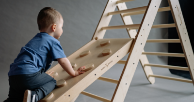 A child climbing up on a wooden play structure.