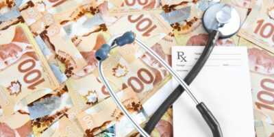 Prescription pad with stethoscope and large amount of canadian one hundred dollar bills, medical/financial concept.