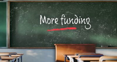 Chalk board that says more funding, school classroom