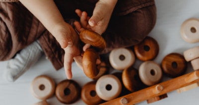 A light-skinned child playing with round wooden toys.