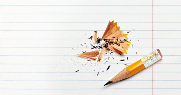 A very short pencil that has been sharpened almost to the end sitting on top of a school notebook